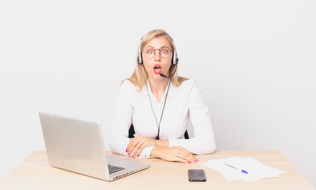 Rubia mujer bonita joven mujer rubia mirando muy conmocionado o sorprendido y trabajando con una computadora portátil