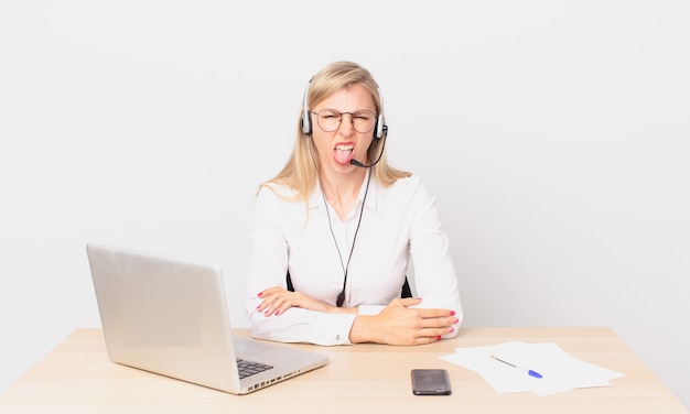 Rubia mujer bonita joven mujer rubia que se siente disgustada e irritada y con la lengua fuera y trabajando con una computadora portátil