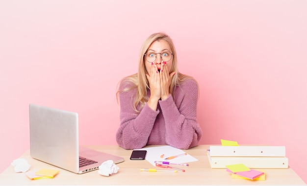 Rubia mujer bonita joven mujer rubia sintiéndose conmocionada y asustada y trabajando con una computadora portátil