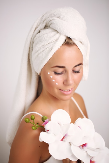 Rubia con natural tocando su cara y una orquídea