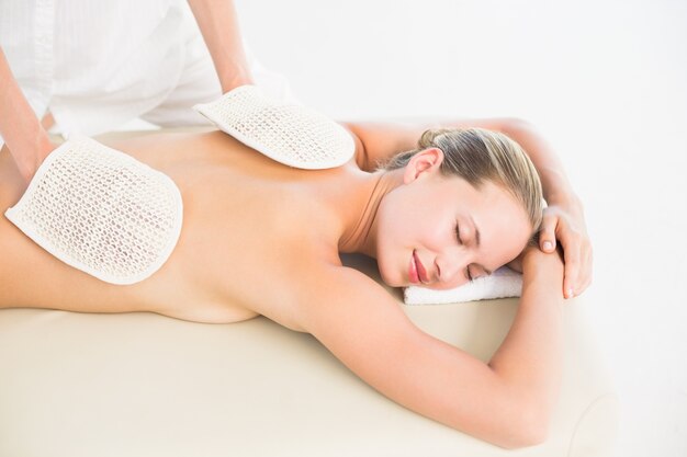 Rubia pacífica disfrutando de un masaje de espalda exfoliante