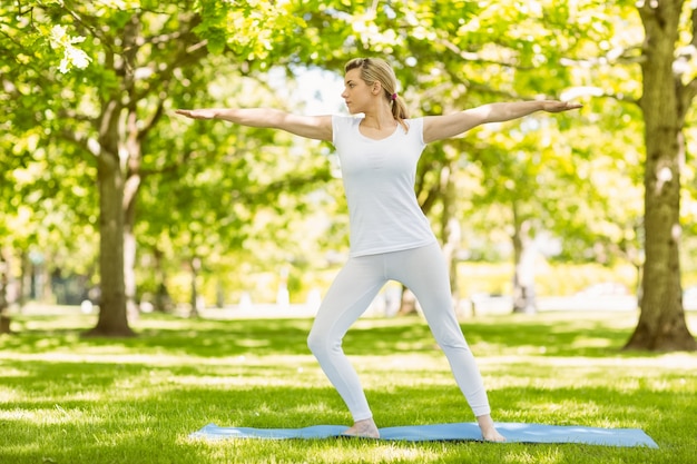 Rubia pacífica haciendo yoga en el parque