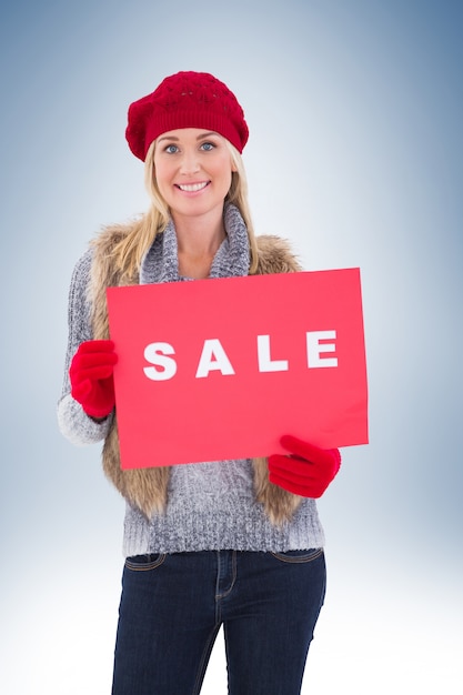 Foto rubia en ropa de invierno con cartel de venta