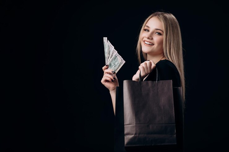 Rubia sosteniendo billetes de dólar y bolsas de compras