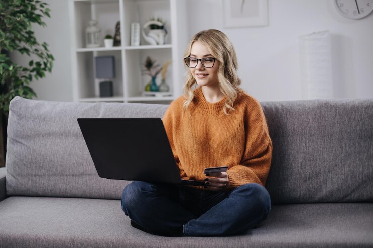 Rubia usando laptop y tarjeta para ir de compras