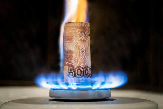 El rublo ruso arde en el fuego. concepto de la subida del precio del gas en Rusia. un billete de 5000 rublos arde en el fuego de una estufa de gas. Suministro de gas caro