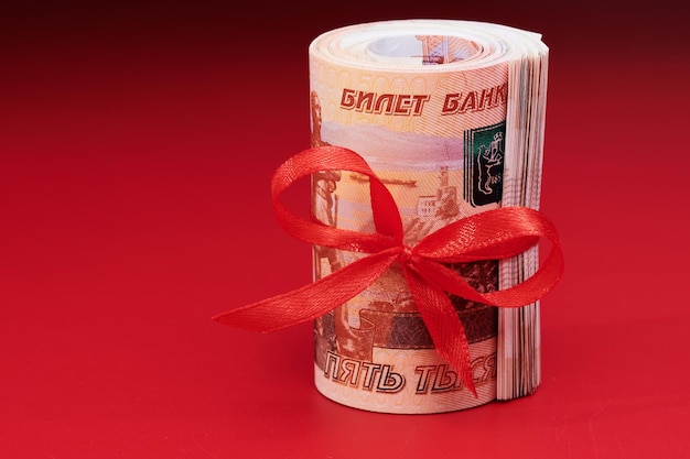 Rublos rusos cinco mil billetes paquete de dinero con cinta roja sobre fondo rojo concepto de regalo