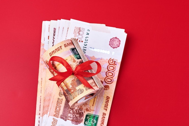 Rublos rusos cinco mil billetes paquete de dinero con cinta roja sobre fondo rojo concepto de regalo