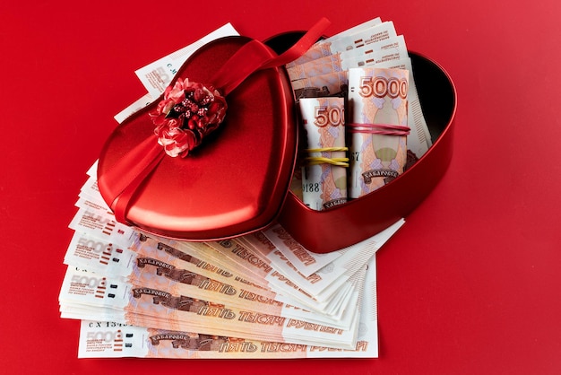 Rublos rusos sobre fondo rojo paquete de cinco mil billetes con cinta roja en concepto de regalo de dinero de caja de corazón