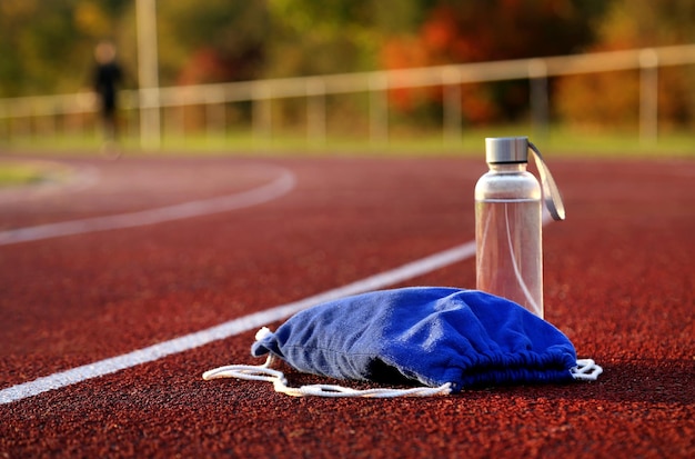 Rucksack und wasserflasche auf der leichtathletikbahn am nachmittag