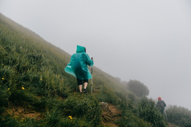 Rucksacktouristen wandern den nebligen Berg hinauf