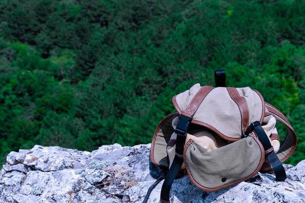 Rucksacktouristenrucksack liegt auf einem grauen Felsen vor dem Hintergrund grüner Bäume Freizeit