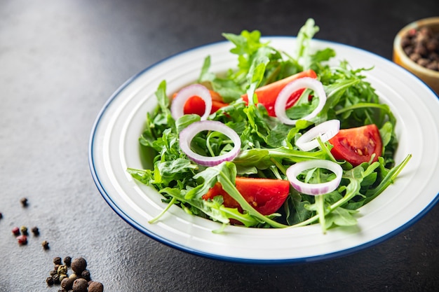 Rúcula e tomate salada de vegetais em um prato porção fresca pronta para comer refeição lanche na mesa