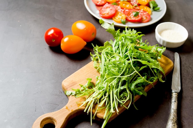 Rúcula fresca en tabla de cortar con tomates ingredientes para cocinar