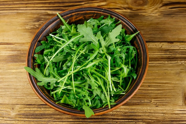 Rúcula verde fresca em tigela de cerâmica em uma mesa de madeira Comida saudável ou conceito vegetariano