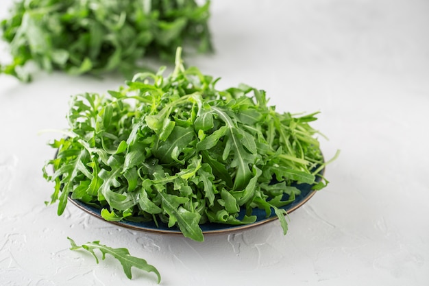 Rúcula verde fresca en un recipiente en la mesa. Rúcula para ensalada