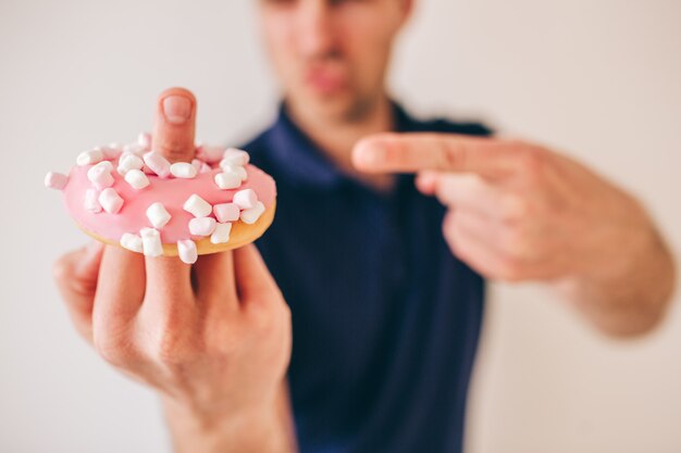 Rude jovem isolado mostrando donut