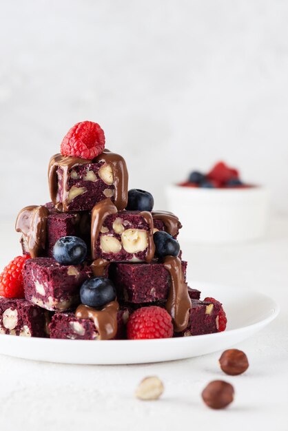 Rüben-Nuss-Brownies mit Blaubeeren, Himbeeren und Schokolade auf einem weißen Teller