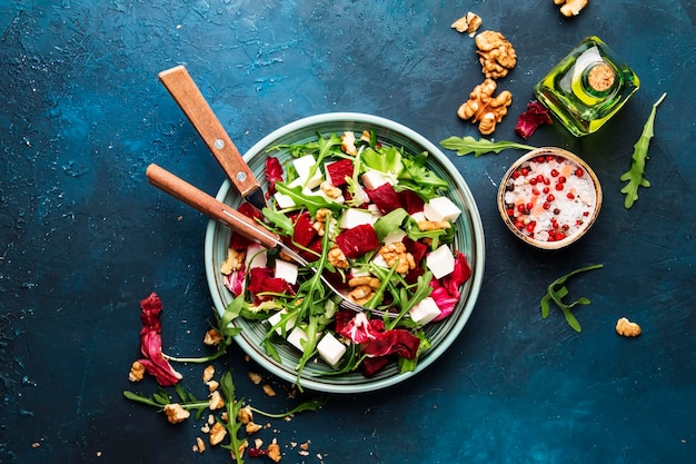 Rüben-Sommersalat mit Rucola-Radicchio-Weichkäse und Walnüssen auf Teller mit Gabel-Dressing....