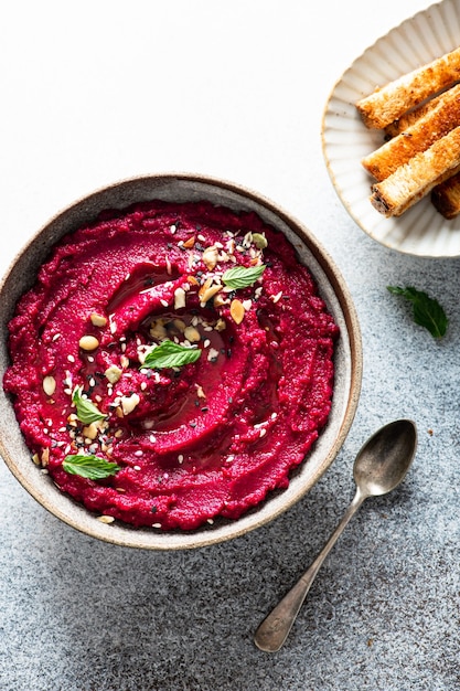 Rübenhummus in einer Keramikschale auf einem konkreten Hintergrund, Draufsicht, selektiver Fokus