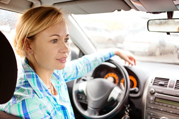 Foto rückansicht der attraktiven frau in der freizeitkleidung, die über ihre schulter schaut, während sie ein auto fährt