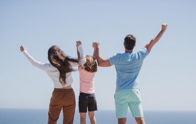 Rückansicht der Familie am Strand, die sich im Sommerurlaub amüsiert, Eltern, die sich an den Händen halten