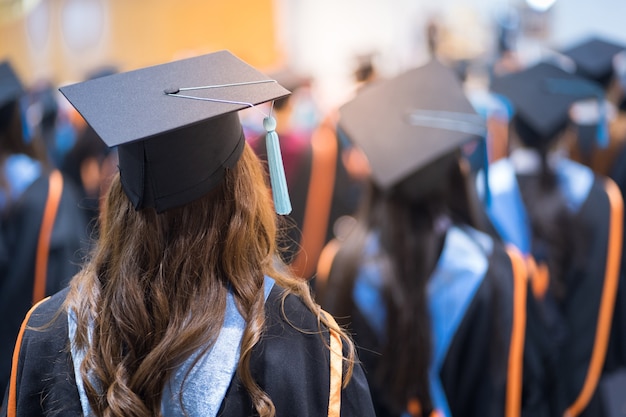 Rückansicht der Hochschulabsolventen, die sich bei der Abschlussfeier der Universität für die Abschlussvergabe anstellen. Die Hochschulabsolventen versammeln sich zur Hochschulabschlussfeier. Masse der Absolventen.