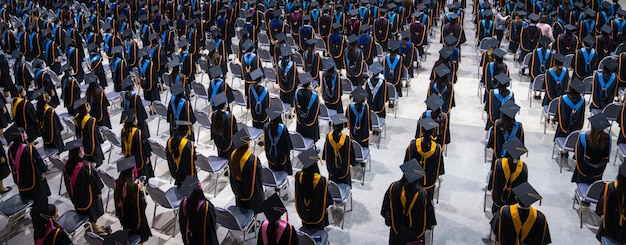 Foto rückansicht der hochschulabsolventen in abschlusskitteln und -mützen