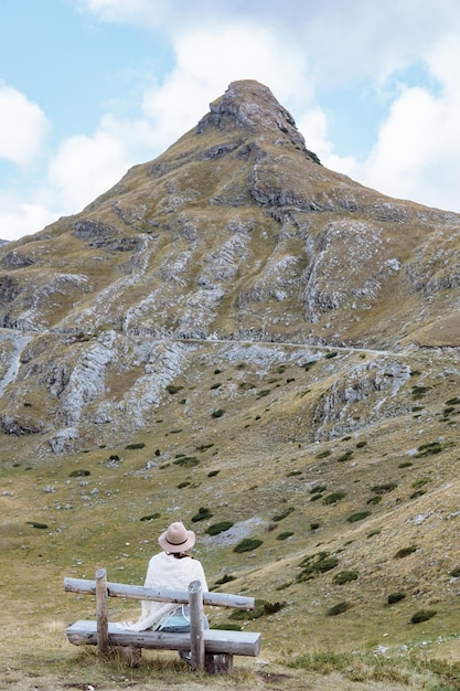 Rückansicht der jungen Dame mit Hut und warmem Poncho auf der Berglandschaft Durmitor Montenegro