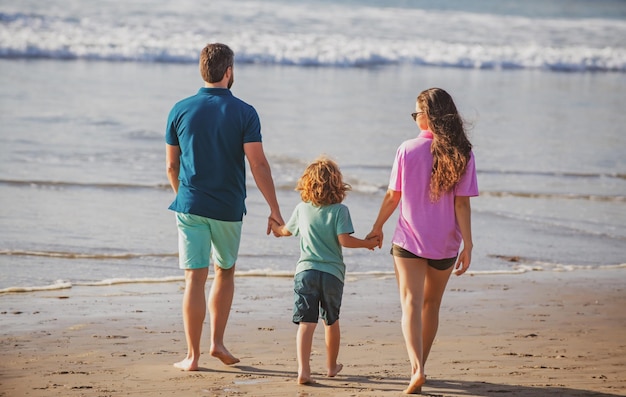 Rückansicht der jungen glücklichen Familie im Strandurlaub