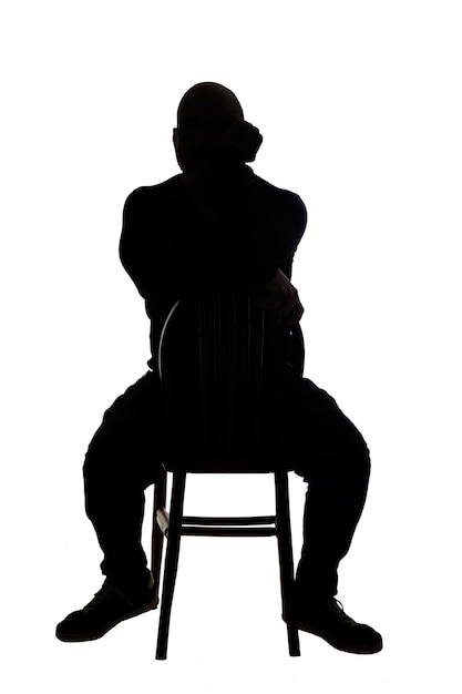 Foto rückansicht der silhouette eines mannes, der mit freizeitkleidung auf einem stuhl sitzt und den stuhl mit der hand aufs gesicht dreht