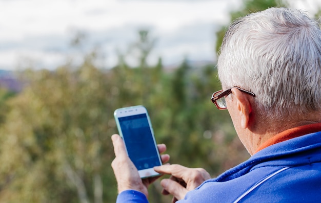 Rückansicht des alten Mannes, der ein Foto mit seinem Handy macht