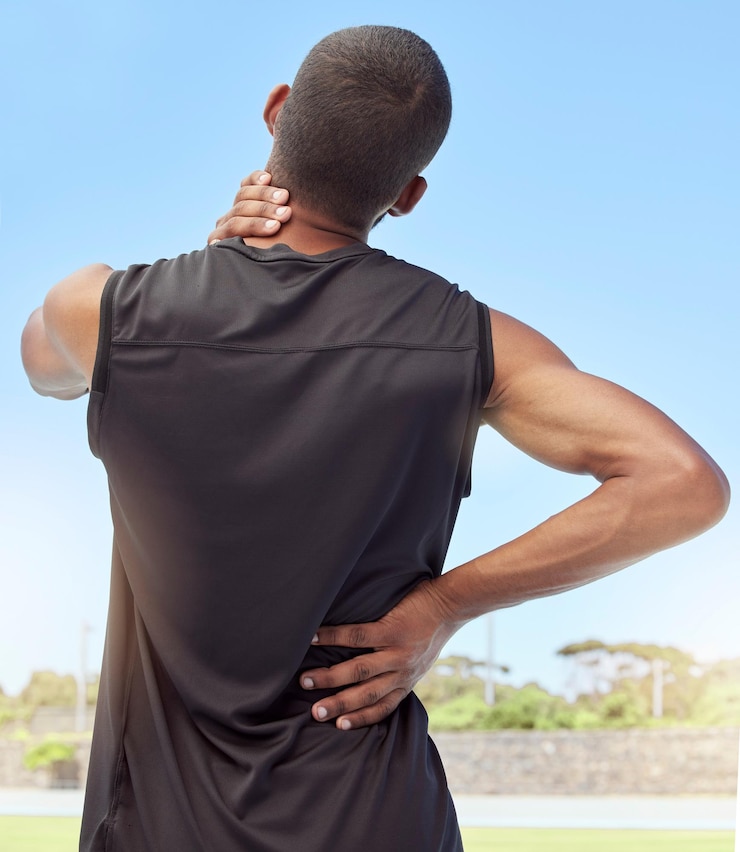 Foto rückansicht des athleten mit nackenschmerzen nahaufnahme rückansicht eines unbequemen jungen sportlers, der auf einem sportplatz steht und seine steifen und entzündeten gelenke hält muskelzerrung aufgrund von verletzungen