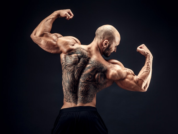 Rückansicht des Aufstellens des Bodybuilders mit Rückentattoo