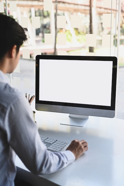 Rückansicht des Geschäftsmannes, der mit Computer arbeitet, während er im modernen Büro sitzt.