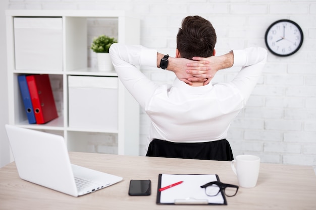 Rückansicht des jungen Geschäftsmannes, der sich im Büro entspannt