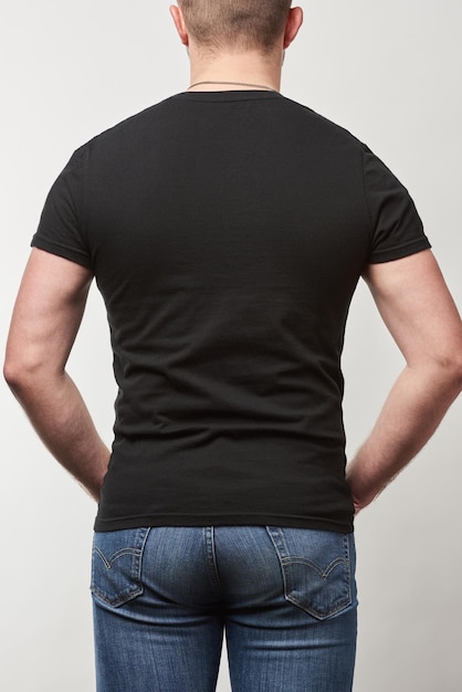 Rückansicht des Mannes in Denim und schwarzem T-Shirt mit Kopierraum isoliert auf grau