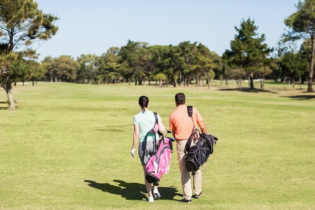 Rückansicht des Paares, das Golftaschen trägt