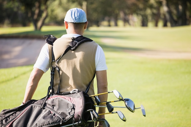 Rückansicht des Sportlers, der eine Golftasche hält