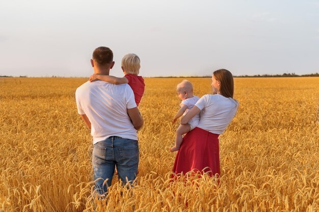 Rückansicht des Vaters Mutter und zwei Kinder im Weizenfeld Junge Familie mit Kindern im Freien