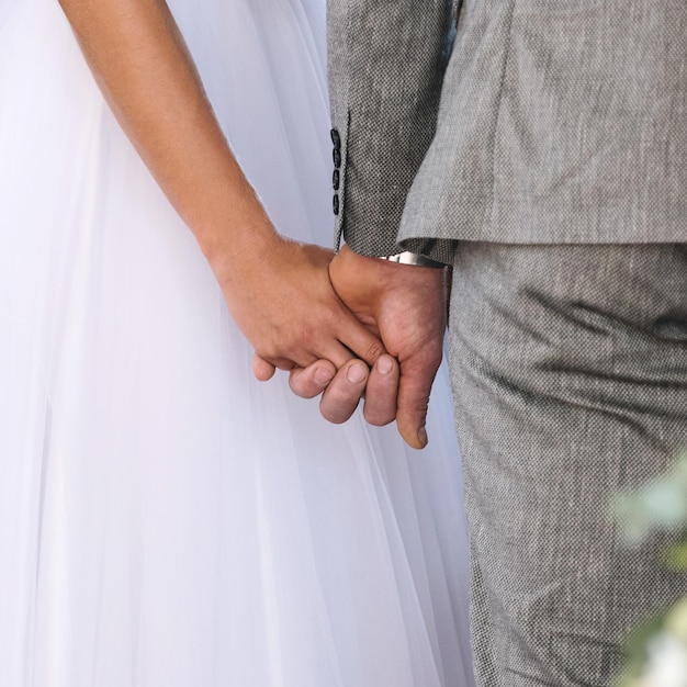 Rückansicht einer Braut im weißen Kleid und des Bräutigams im Anzug, die sich in der Kirche an den Händen halten