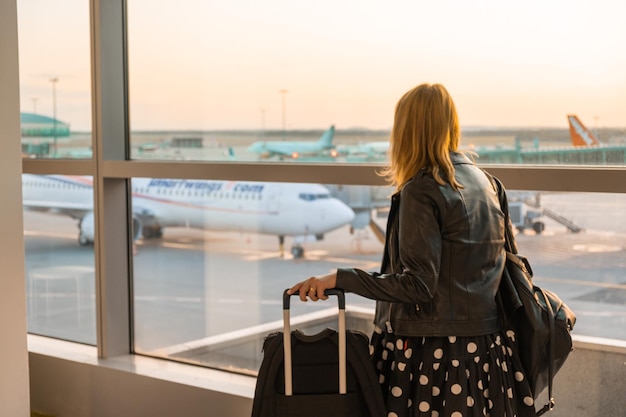 Rückansicht einer Frau, die am Flughafen steht und auf das Boarding wartet