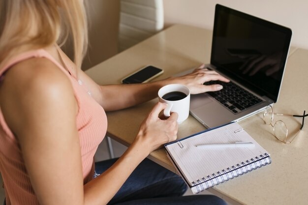 Rückansicht einer jungen Frau, die zu Hause an einem Laptop arbeitet