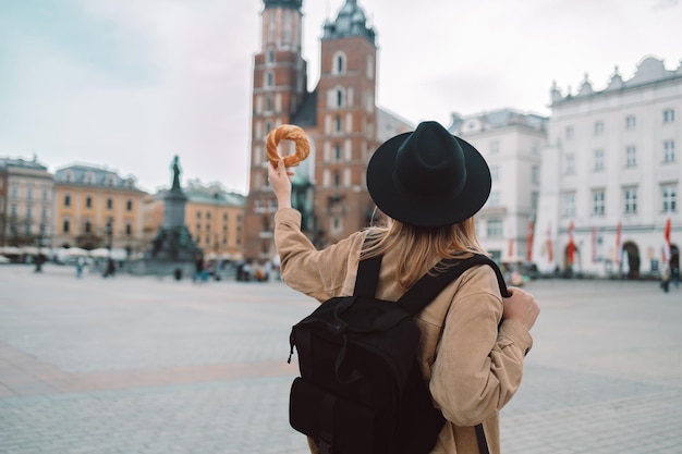 Rückansicht einer jungen Touristin in der Hand, die Bagel Obwarzanek Brezel mit traditionellem polnischen Snack hält