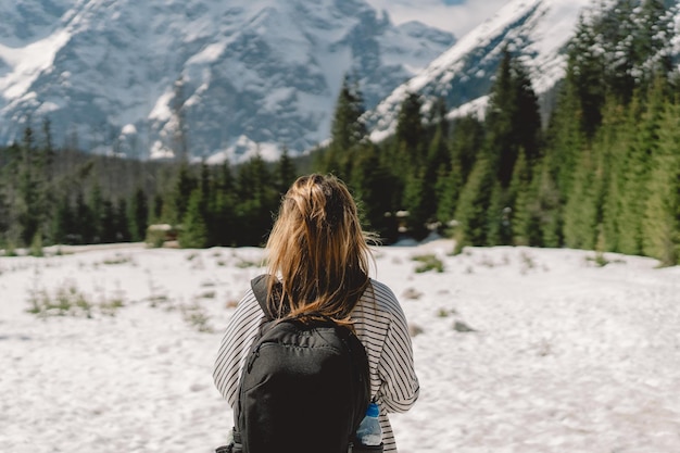 Rückansicht einer Reisenden mit Rucksack, die allein im Tal des Tatra-Gebirges in Polen unterwegs ist