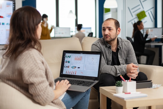 Rückansicht einer Unternehmerin, die mit Laptop auf der Couch sitzt