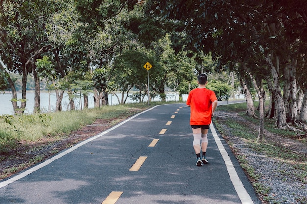 Rückansicht eines asiatischen Mannes, der im Sommer im Park joggt