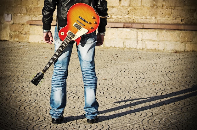 Foto rückansicht eines gitarristen, der mit einem gitarren-vintage-effekt steht