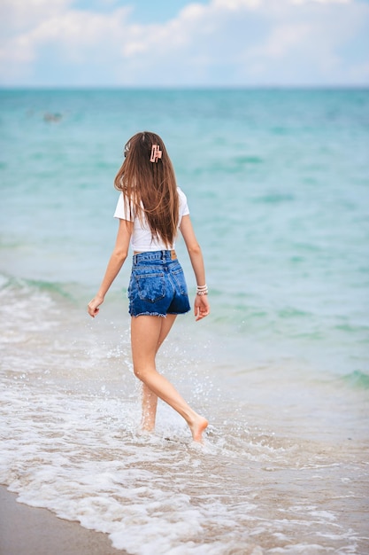 Rückansicht eines glücklichen Mädchens, das am Strand läuft