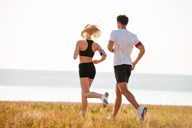 Foto rückansicht eines jungen fitness-mannes und einer jungen frau, die im freien joggen